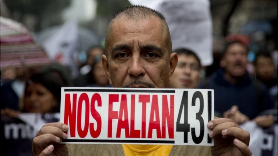 Мужчина держит табличку с надписью на испанском: «Нам не хватает 43» во время марша, посвященного годовщине исчезновения 43 студентов колледжа в Мехико 26 сентября 2015 г.