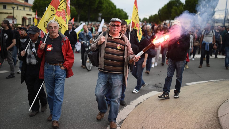 Демонстрант несет дорожную сигнальную ракету 26 мая 2016 года в Нанте, западная Франция