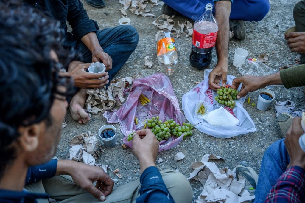Yer sofrasında yemek yiyen göçmenler