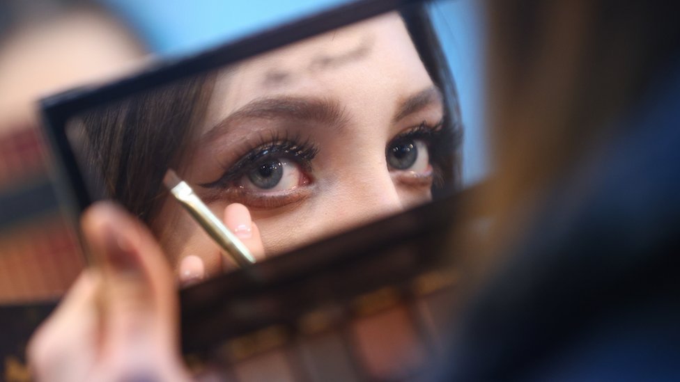 Женщина наносит макияж глаз