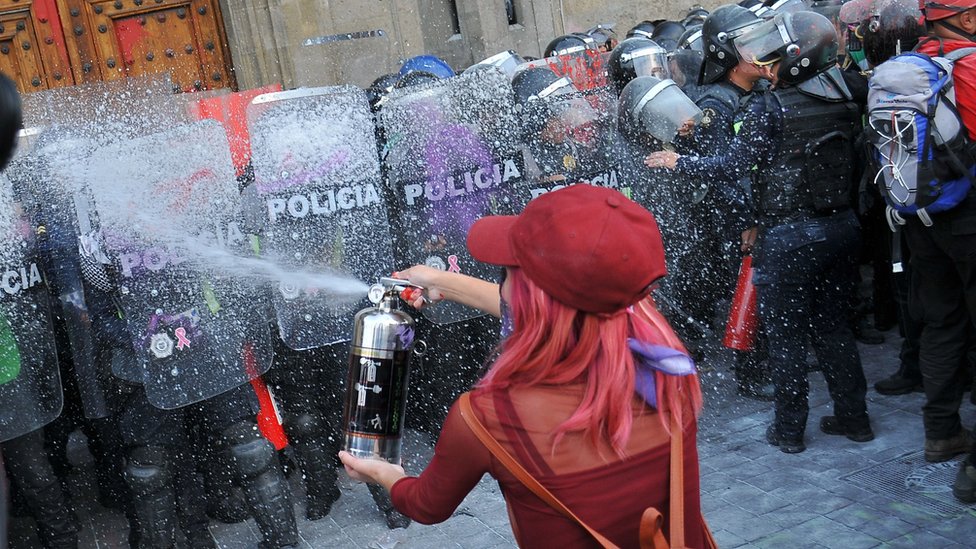 Женщина сталкивается с полицией во время акции протеста во время Международного женского дня в Мехико