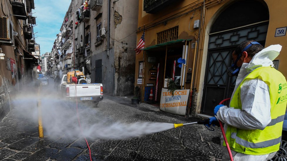 Hombre desinfecta una calle de Nápoles.