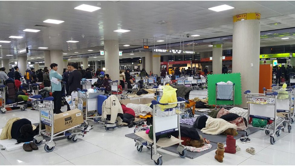 На фотографии, сделанной камерой смартфона, показаны пассажиры, спящие в зале вылета международного аэропорта Чеджу в Чеджу, Южная Корея, начало 25 января 2016 г.