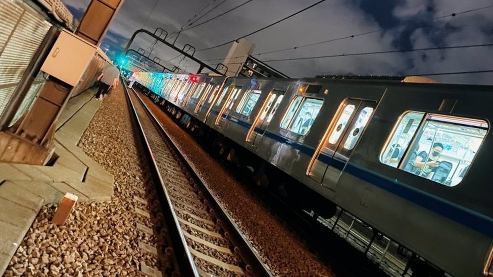 People walk along railway tracks after a knife attack on a Tokyo train