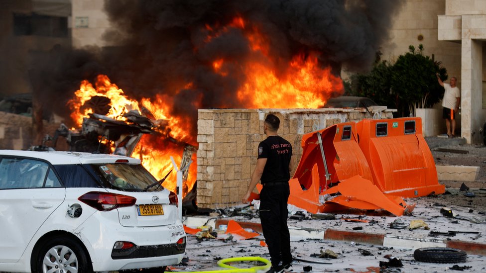 Čovek stoji na putu dok vatra gori nakon što su rakete lansirane iz pojasa Gaze, u Aškelonu, Izrael