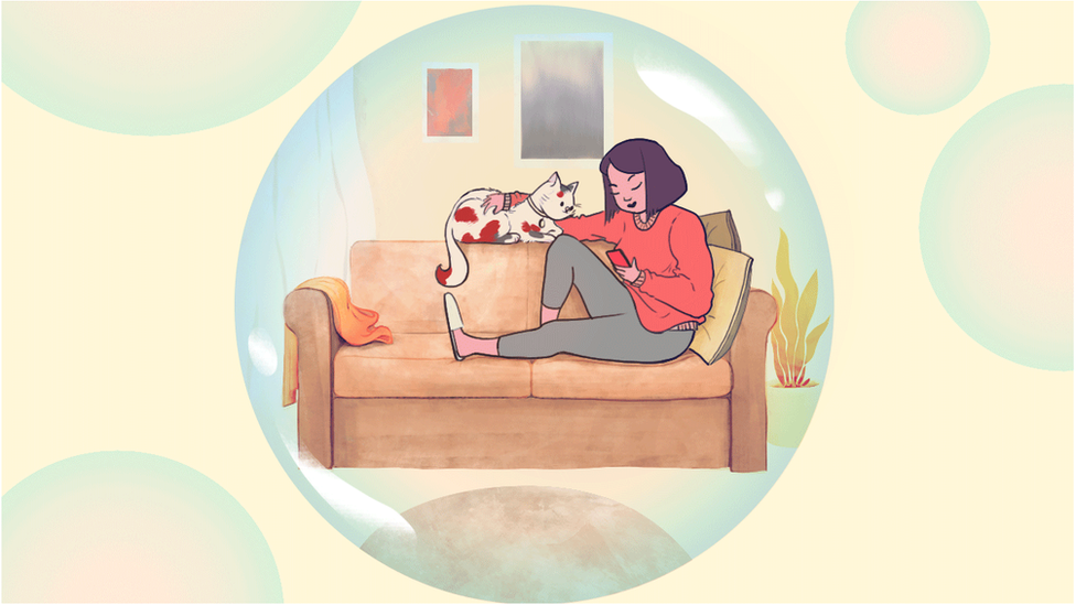 Женщина смотрит в свой телефон на диване с кошкой в ??большом пузыре