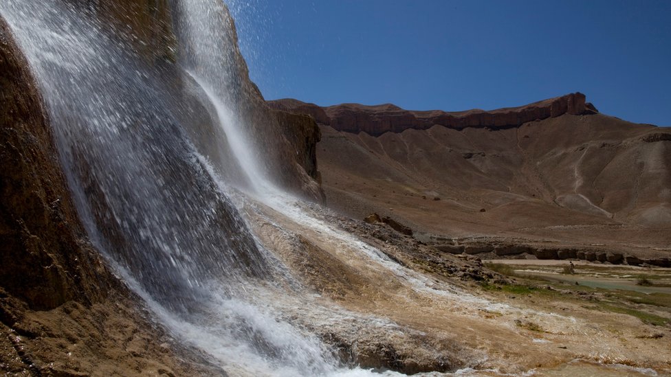 Водопад, созданный естественными "травертиновыми" дамбами, контрастирует с высокими красными скалами пустыни в национальном парке Банд-Э-Амир 6 сентября 2009 года в Банд-Э-Амир, Афганистан.