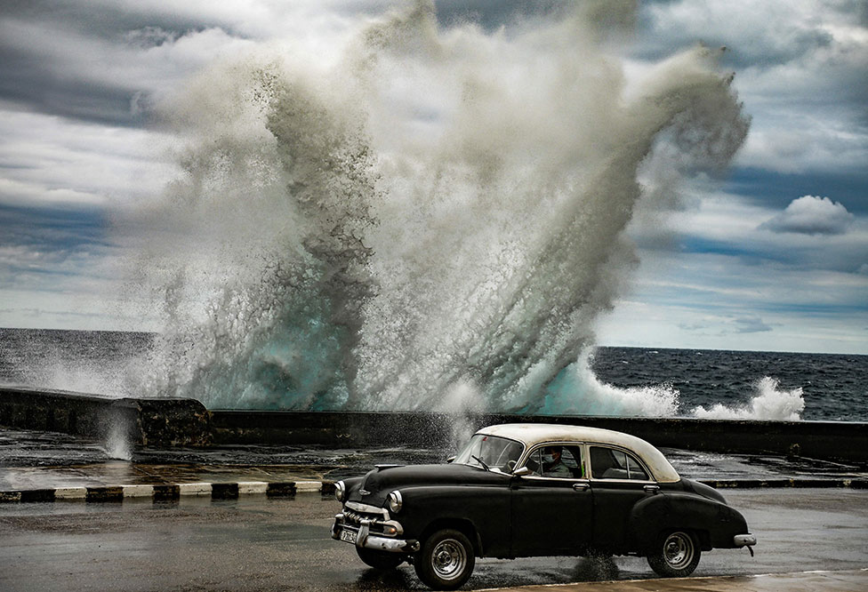 سيارة أمريكية قديمة تمر بجانب أمواج عاتية خلقتها رياح شديدة في مدينة هافانا في كوبا.