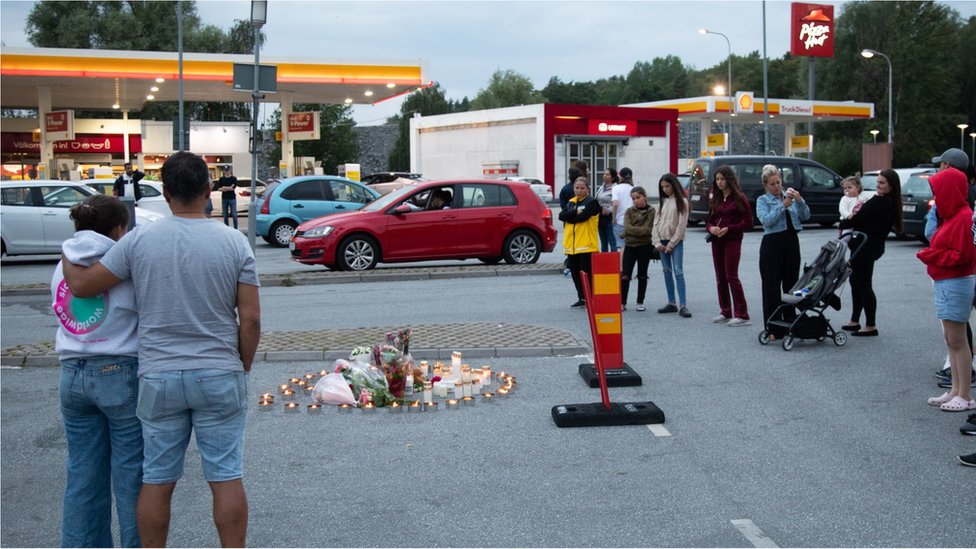 Люди возлагают свечи и цветы на то место, где возле заправочной станции в Боткирке, к югу от Стокгольма, Швеция, 3 августа 2020 года была застрелена двенадцатилетняя девочка.