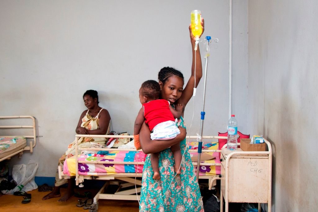 Mother helps baby have intravenous medication in a Madagascar clinic