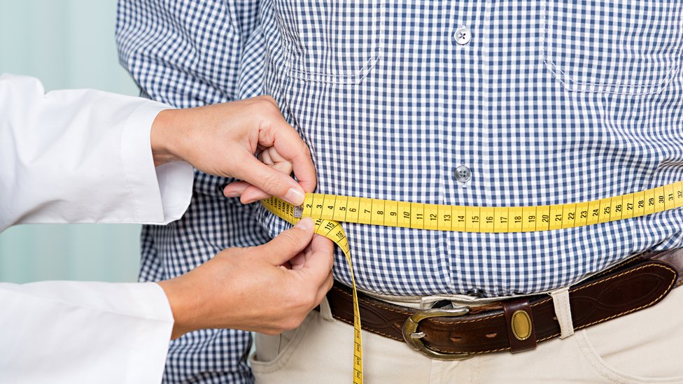 Doctor midiendo el sobrepeso de un hombre.