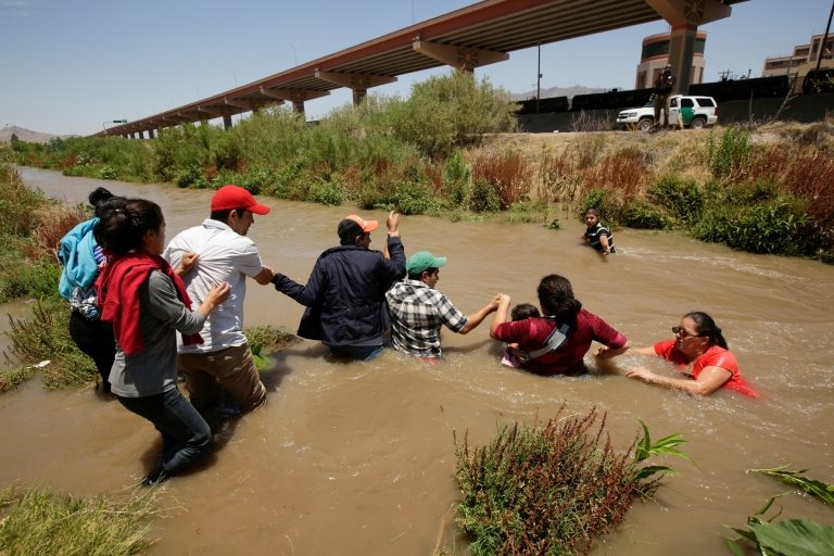 Migrantes cruzando un río fronterizo
