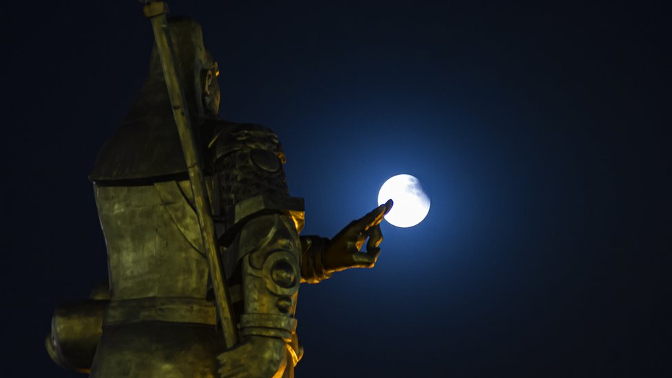 The lunar eclipse is observed over a sculpture in the city of Yuncheng, China. Photo: 26 May 2021