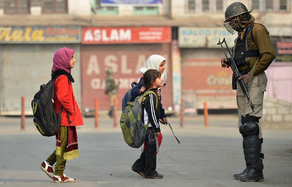 Anak sekolah Kashmir melewati paramilite India.