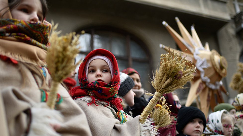 Ukrayna'da buğdaylardan hazırlanmış Noel dekorasyonu tutan bir kız çocuğu.