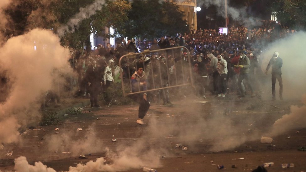 Во время столкновений с силами безопасности в Бейруте демонстранты сдвигают металлические заграждения, охваченные слезоточивым газом