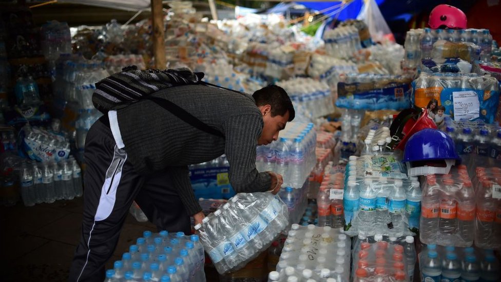 La desorganización en la entrega y reparto de ayuda sigue siendo un problema en el operativo tras el terremoto. Hombre con botellas de agua.