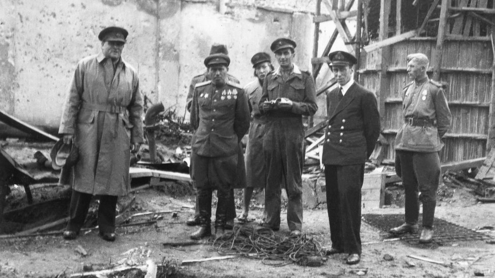 Richard Dimbleby, BBC War Correpondent outside Hitler's underground shelter in Berlin, with the Russian major who is in charge of the Chancellery, and others