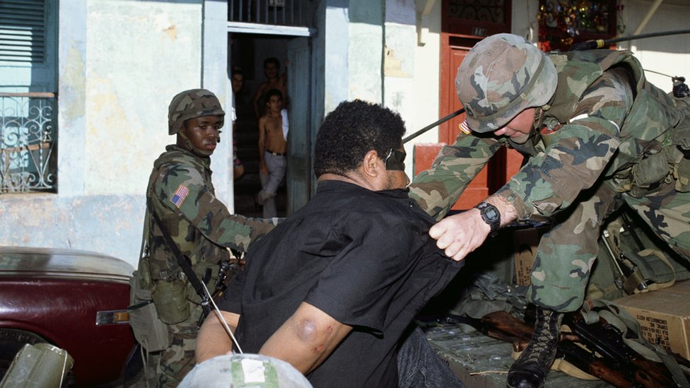 American soldiers detain a man caught looting during the invasion of Panama.