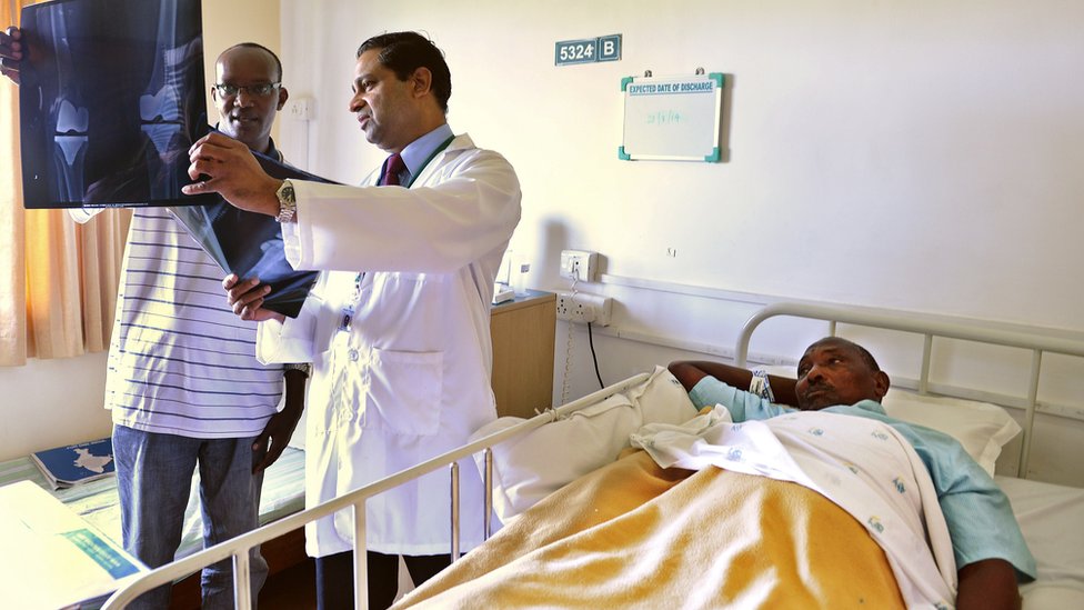 Врач показывает рентгеновский снимок дежурному пациенту из Нигерии (справа), перенесшему операцию в больнице Аполло в Ченнаи, Индия