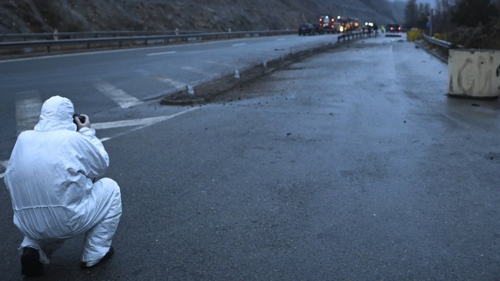 An investigator takes a picture of the wreckage of a bus with North Macedonian plates that caught fire on a highway