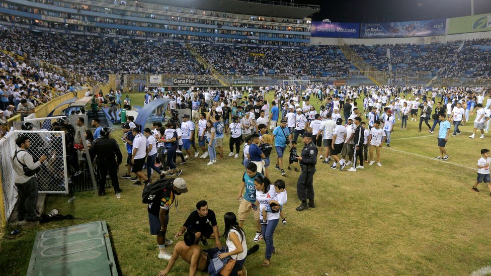 Los simpatizantes son ayudados por otros luego de una estampida durante un partido de fútbol entre Alianza y FAS en el estadio Cuscatlán en San Salvador.