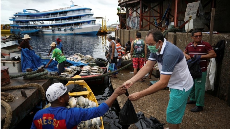 Homem compra peixe no porto em Manaus