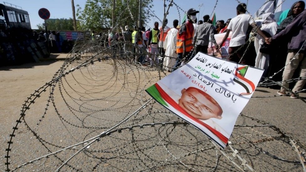 Листовка с изображением Ахмеда аль-Хайра, задержанного суданского демонстранта, который умер во время содержания под стражей, висит на колючей проволоке, когда люди собираются перед судом в Омдурмане, недалеко от столицы Судана, Хартума, 30 декабря 2019 г.