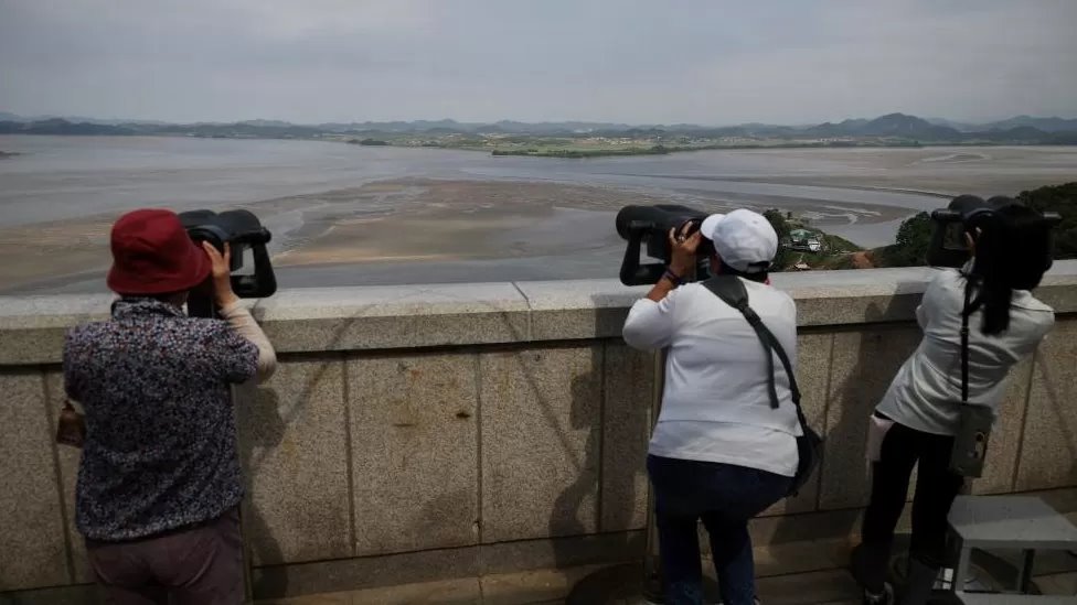 Tourists in South Korea looking north across the Demilitarised Zone that separates the two countries