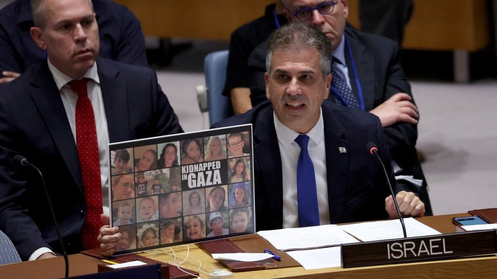 Israeli Foreign Minister Eli Cohen holds up a poster showing kidnapped Israeli children during a speech at the UN Security Council in New York (24 October 2023)
