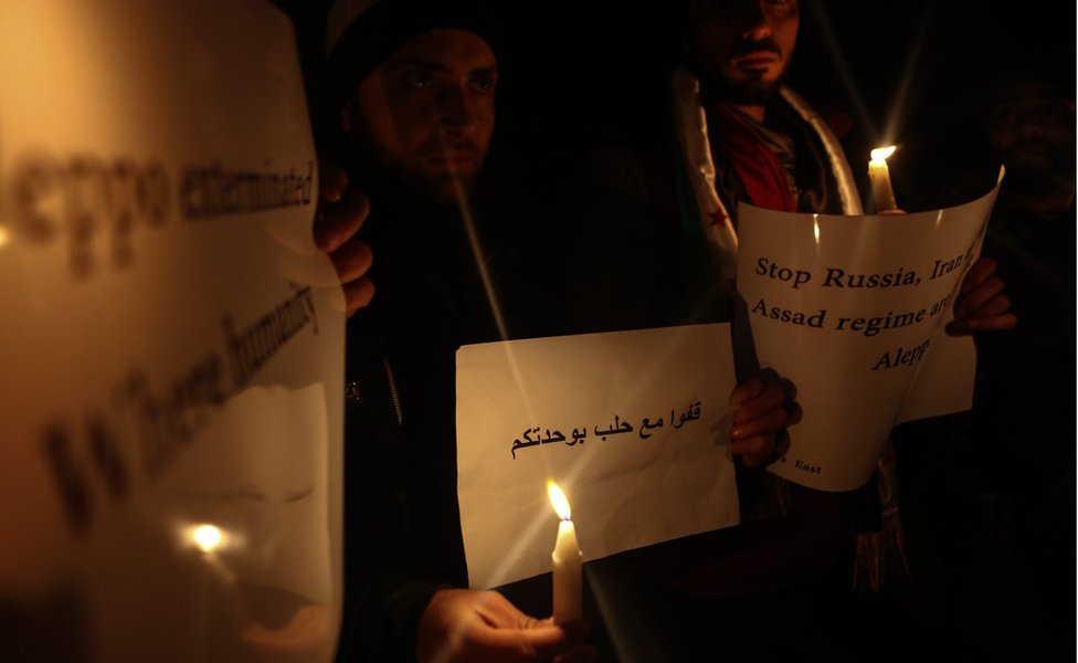 Активисты держат плакаты во время собрания при свечах в знак солидарности с народом Алеппо в свете недавних событий, о которых сообщается в осажденном городе, в Думе, район Восточная Гута, недалеко от Дамаска,