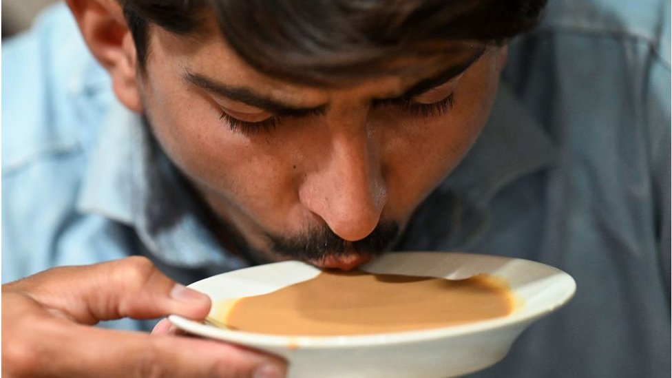 Un hombre bebe té de un platillo en un restaurante en Islamabad