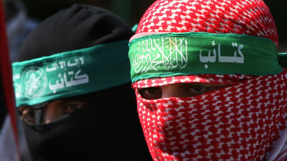 Abu Obayda wearing a red keffiyeh around his head that keeps his identity secret