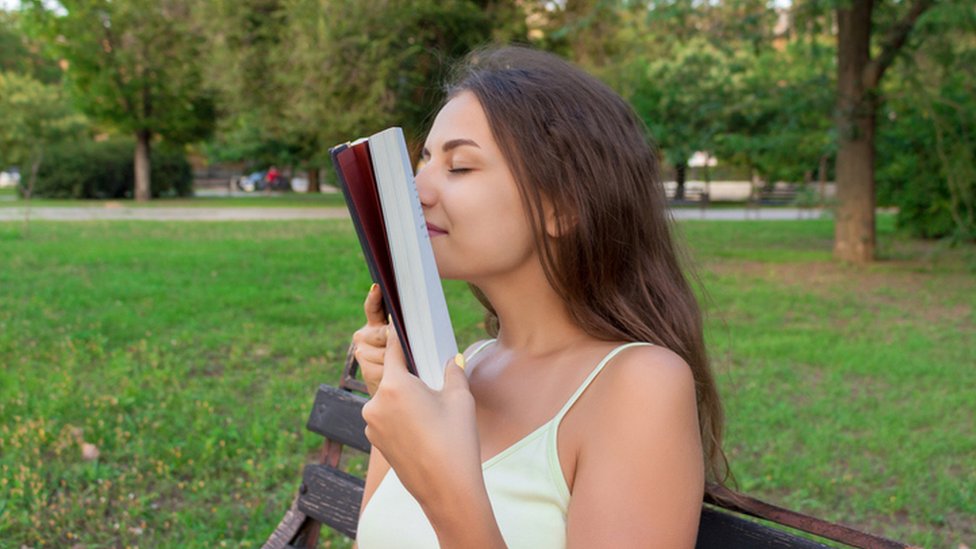 Una joven huele un libro.