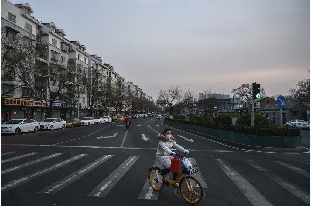 一名北京婦女在街上騎自行車時戴著防護口罩