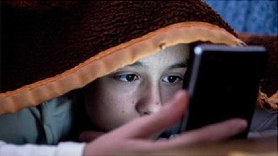Девочка-подросток пользуется телефоном в постели