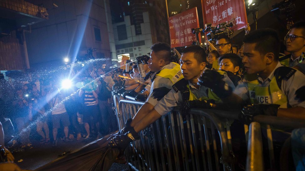 Полиция использует перцовый баллончик, чтобы остановить протестующих у здания китайского офиса Лиасона в Гонконге 6 ноября 2016 года во время акции протеста против ожидаемого толкования конституции города - Основного закона - Постоянным комитетом Национального народного конгресса Китая Комитет