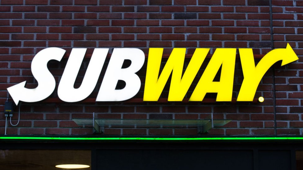 На этом снимке крупным планом видно, как логотип цепи сэндвичей Subway прикручен к кирпичной стене.