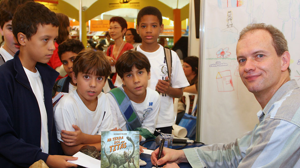 Kellner también es autor de obras para niños como "En la Tierra de los Titanes". Foto: gentileza Alexander Kellner Kellner rodeado de niños autografiando un libro Foto: gentileza Alexander Kellner