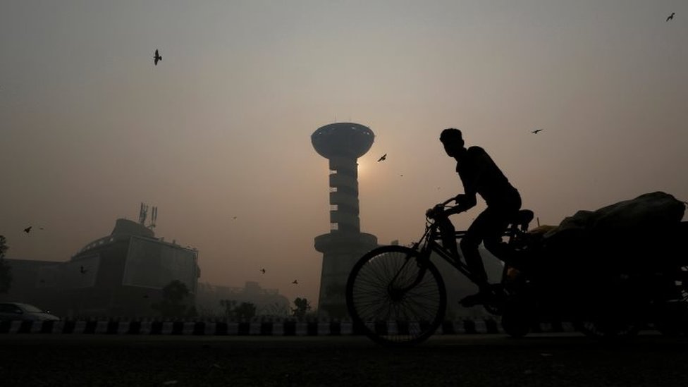 Рикша проезжает мимо торгового центра посреди густого смога в Нью-Дели, Индия, 31 октября 2016 г.