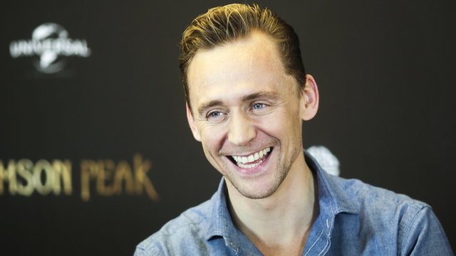 Tom Hiddleston happily grins for the cameras promoting his current film, a gothic horror called Crimson Peak