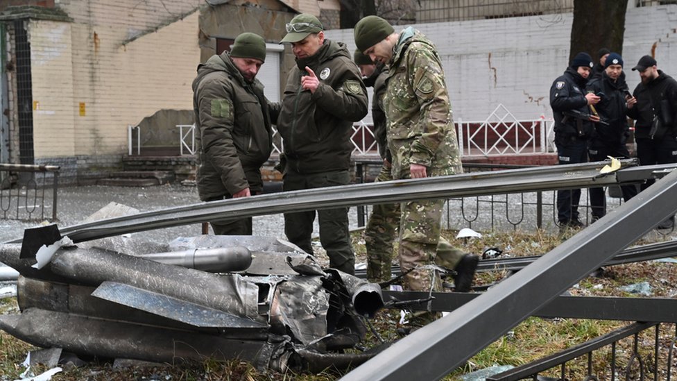 En Kiev, la policía y el personal de seguridad inspeccionan los restos de un proyectil en una calle.