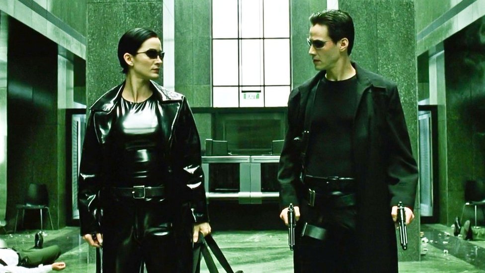 Carrie-Anne Moss e Keanu Reeves trajados como seus personagens Trinity e Neo no filme de 1999