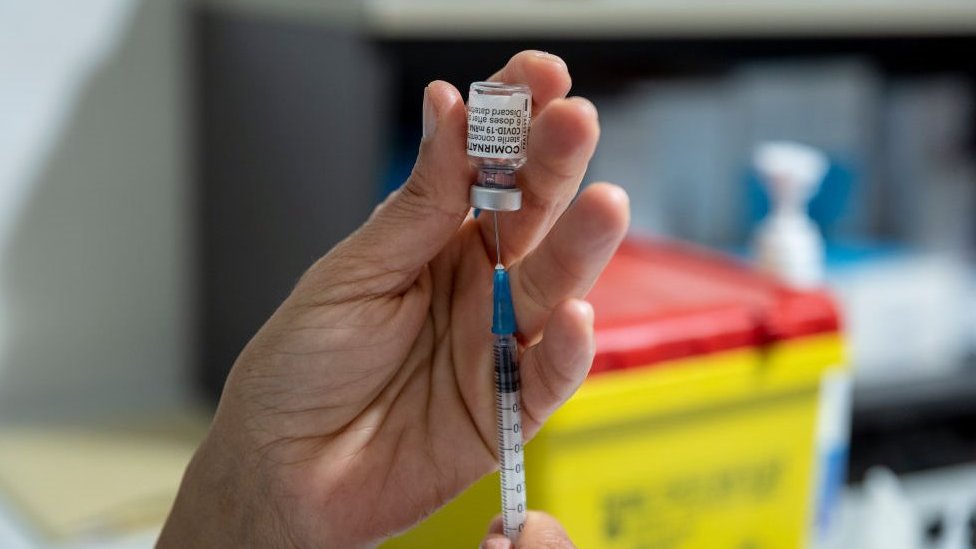 醫護人員正將疫苗從小瓶中抽入注射器