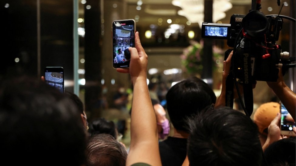 Pessoas de costas filmam hotel com celulares