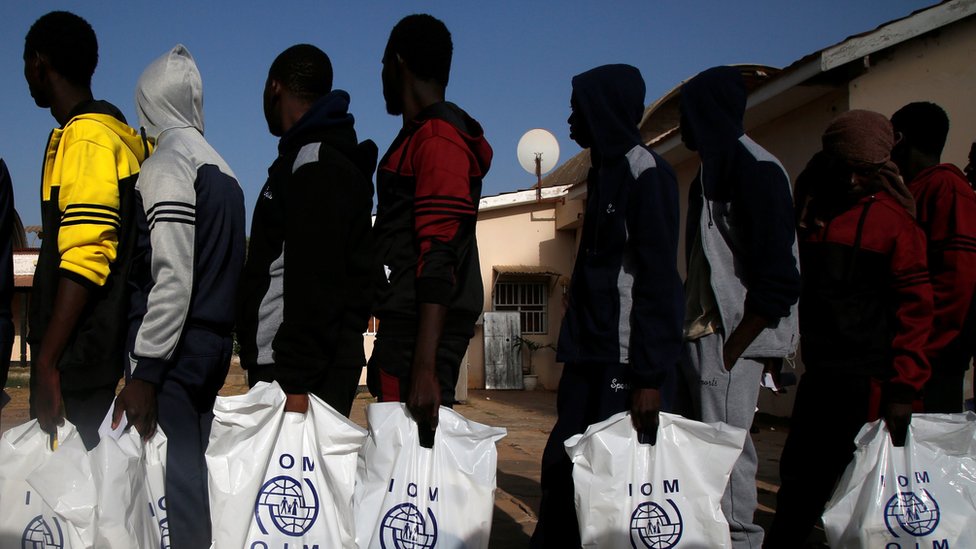 Гамбийские мигранты, добровольно вернувшиеся из Ливии, стоят в очереди с пластиковым пакетом Международной организации по миграции (МОМ), ожидая регистрации в аэропорту Банжула, Гамбия 4 апреля 2017 г.