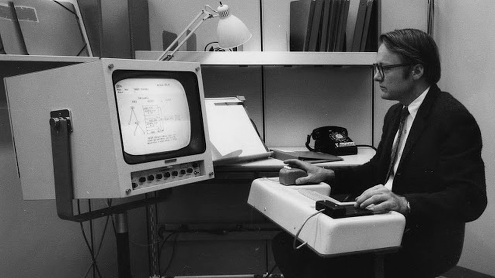 Молодой Билл Инглиш сидит за старым компьютерным терминалом 1960-х годов на архивной фотографии 1960-х годов