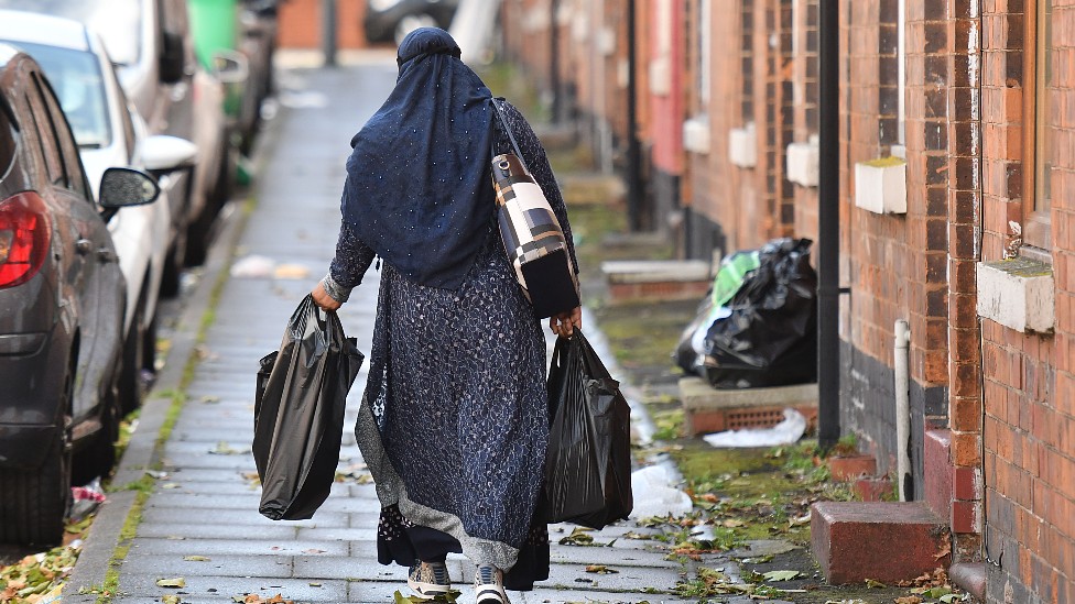 Una mujer cubierta con hiyab camina por una calle en Inglaterra