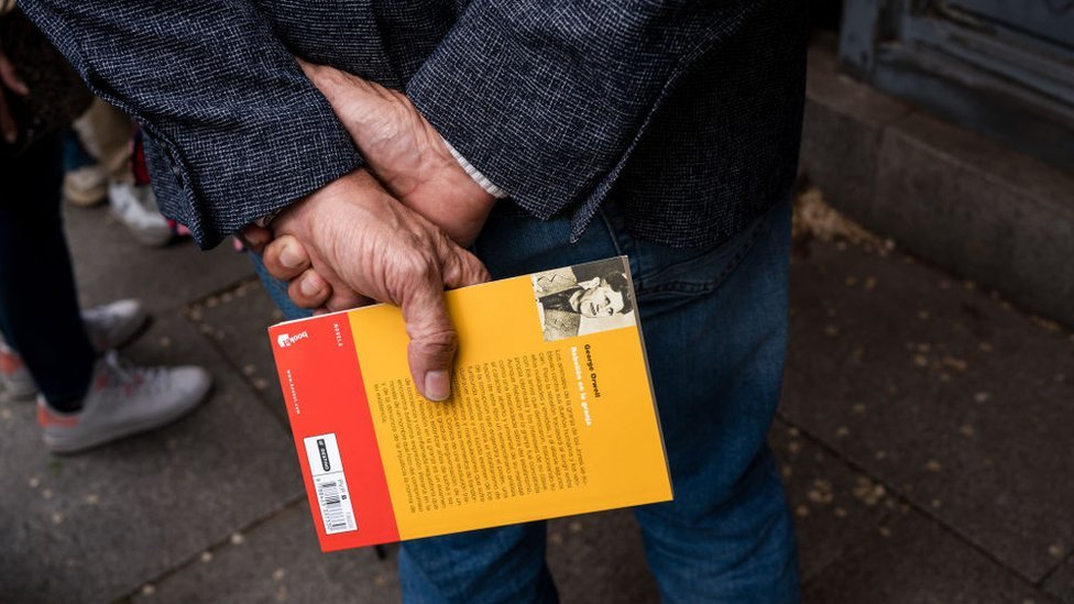 Un hombre sujetando una copia de "Rebelión en la granja"