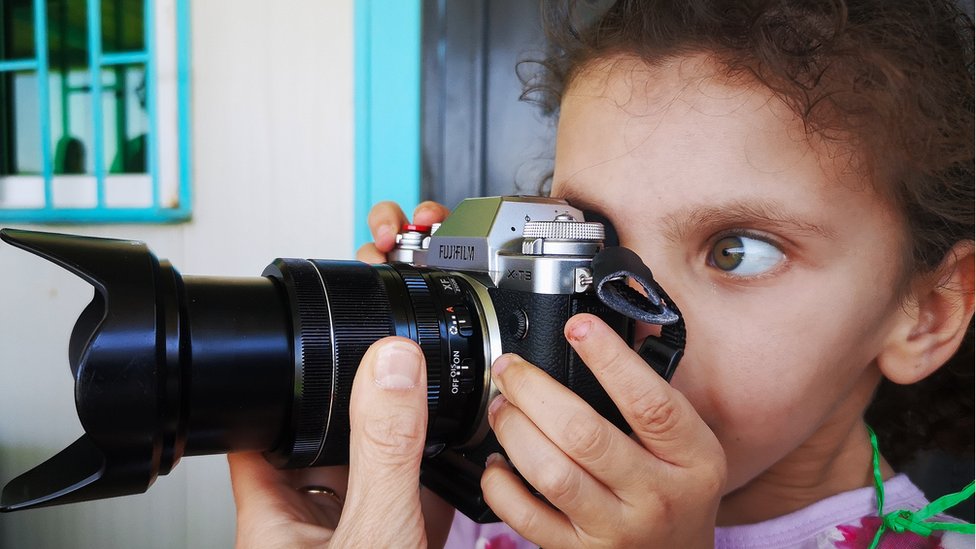 Девушка-беженка с фотоаппаратом